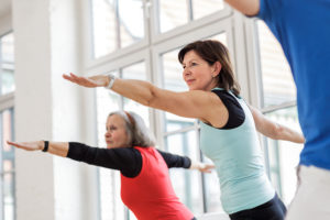 Senior woman with other seniors in a yoga class. Horizontal shot.