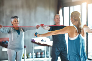 Shot of a senior man and woman using resistance bands with the help of a physical therapist
